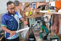 Idriosman menghiris kertas menggunakan parang yang baru diasah bagi memastikan ketajaman matanya.