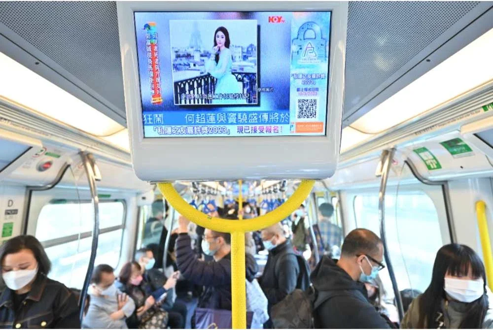 Orang ramai melihat laporan berita mengenai model dan pempengaruh Hong Kong, Abby Choi menerusi skrin di dalam sebuah kereta api di Hong Kong pada Februari 2023. Foto: AFP