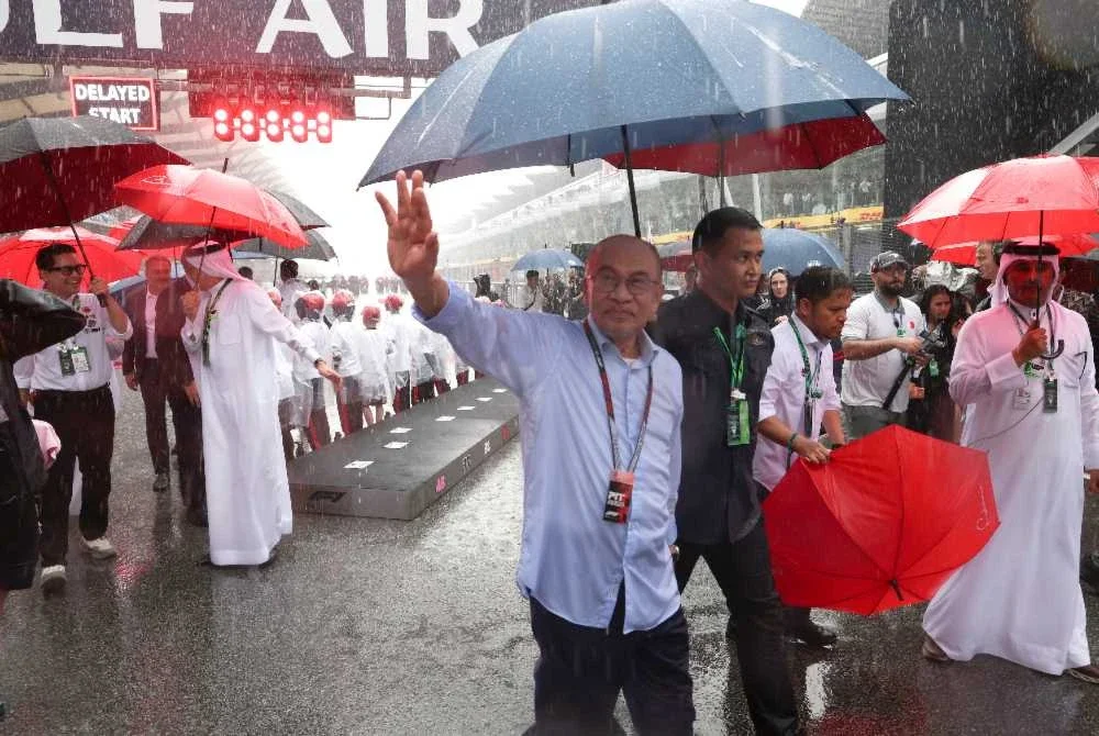 Perdana Menteri, Datuk Seri Anwar Ibrahim dipayungi pengiring ketika berada di Litar Antarabangsa Sepang sempena perlumbaan Formula 1 Gulf Air Bahrain Grand Prix di Malaysia semalam. Foto: Bernama