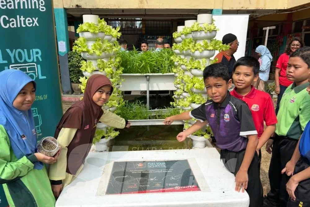 Murid SK Kubang Kerian 2 memberi makan kepada ikan talapia yang diternak.