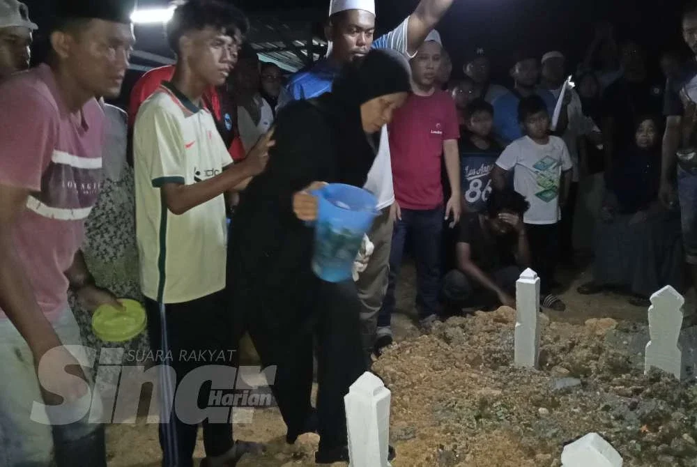 Julaiha menyiram air di atas pusara anak-anaknya di Tanah Perkuburan Islam Kampung Parit Haji Siraj, Pontian pada Khamis.