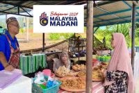 Mohd Sayuti (kanan) menjual pisang goreng di gerai beratapkan zink di Kuala Krai.
