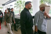 Muhammad Fadzil (kiri) dan Md Fadzilah (kanan) diiringi pegawai SPRM keluar dari Mahkamah Sesyen pada Khamis.