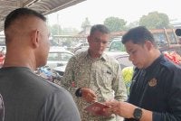 Hamidi (tengah) melihat dokumen IDP yang dirampas JPJ.