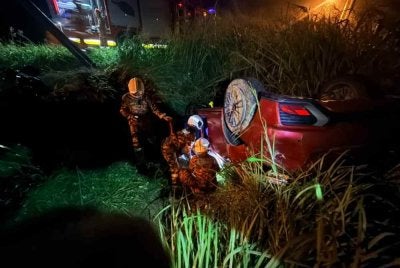 Pasukan bomba melakukan kerja-kerja menyelamat mengeluarkan tiga mangsa dari parit dalam kemalangan membabitkan dua kenderaan di Kampung Teluk Sareh, Kampung Gajah pada Khamis. Foto: JBPM Perak