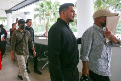 Muhammad Fadzil (kiri) dan Md Fadzilah (kanan) diiringi pegawai SPRM keluar dari Mahkamah Sesyen pada Khamis.
