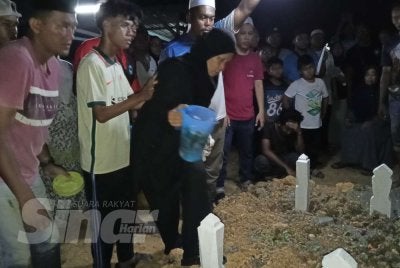 Julaiha menyiram air di atas pusara anak-anaknya di Tanah Perkuburan Islam Kampung Parit Haji Siraj, Pontian pada Khamis.