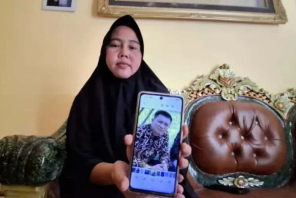 Rika menunjukkan foto suaminya, Hardiansyah, yang meninggal dunia selepas mengadu sesak nafas ketika bangun pada waktu pagi. Foto: Agensi