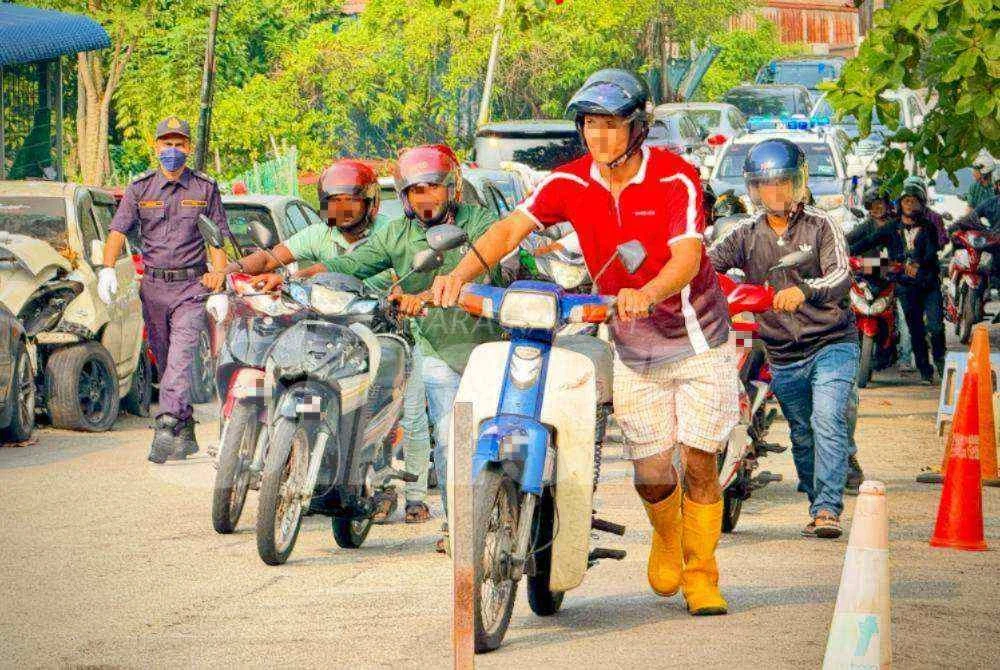Penunggang motosikal warga asing menolak motosikal masing-masing dalam Operasi PeWA yang diadakan di George Town pada Jumaat.