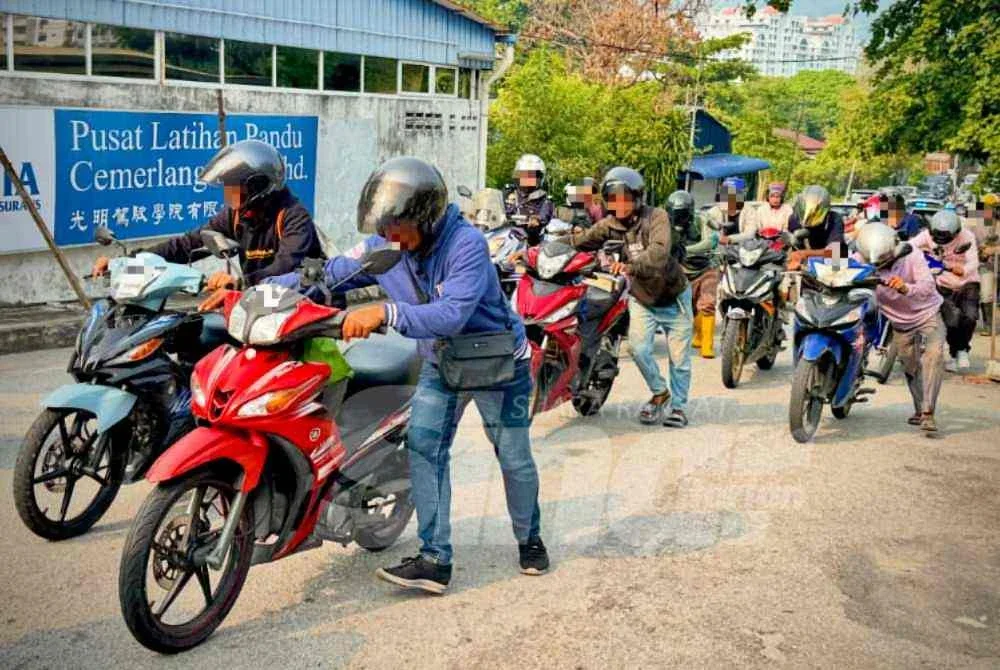 Penunggang motosikal warga asing menolak motosikal masing-masing dalam Operasi PeWA yang diadakan di George Town pada Jumaat.