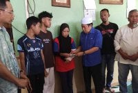 Ahmad (tiga dari kiri) menyerahkan sumbangan kepada keluarga tiga beradik yang maut di Kampung Parit Haji Siraj, Pontian.