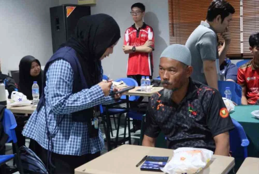 Interaksi seorang peserta dengan petugas program menggunakan telefon pintar menonjolkan kepentingan pendekatan bersemuka dalam memahami keperluan komuniti.