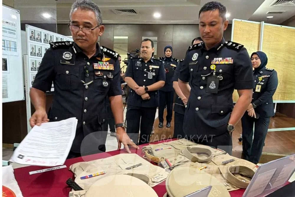 Adzli (kiri) menunjukkan barang rampasan dan baju seragam polis negara India yang digunakan scammer.