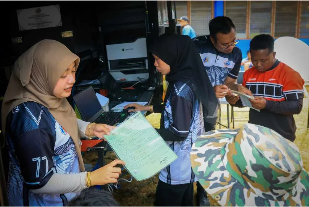 Kakitangan JPN membantu penduduk kampung yang hadir memperbaharui dokumen pengenalan diri pada Program Literasi Pendaftaran sempena sambutan Hari Pendaftaran Negara ke-78 Peringkat Kelantan di Pos Balar, Gua Musang pada Selasa.
