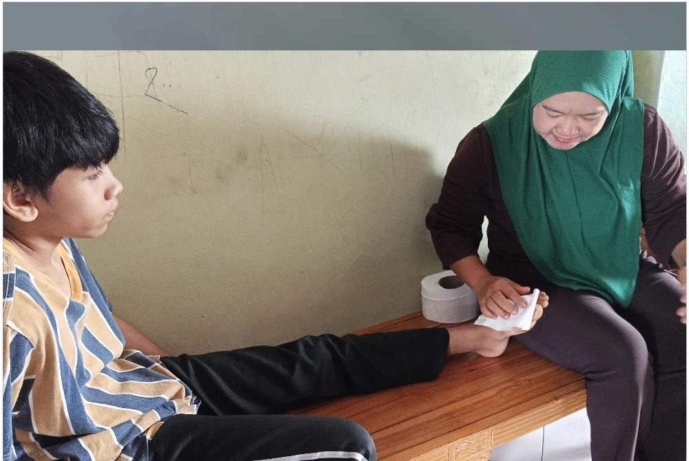 Norliza membersihkan kesan luka pada kaki Alif yang cedera akibat digigit anjing liar di kawasan Perumahan Rakyat Lima Kedai, Iskandar Puteri.