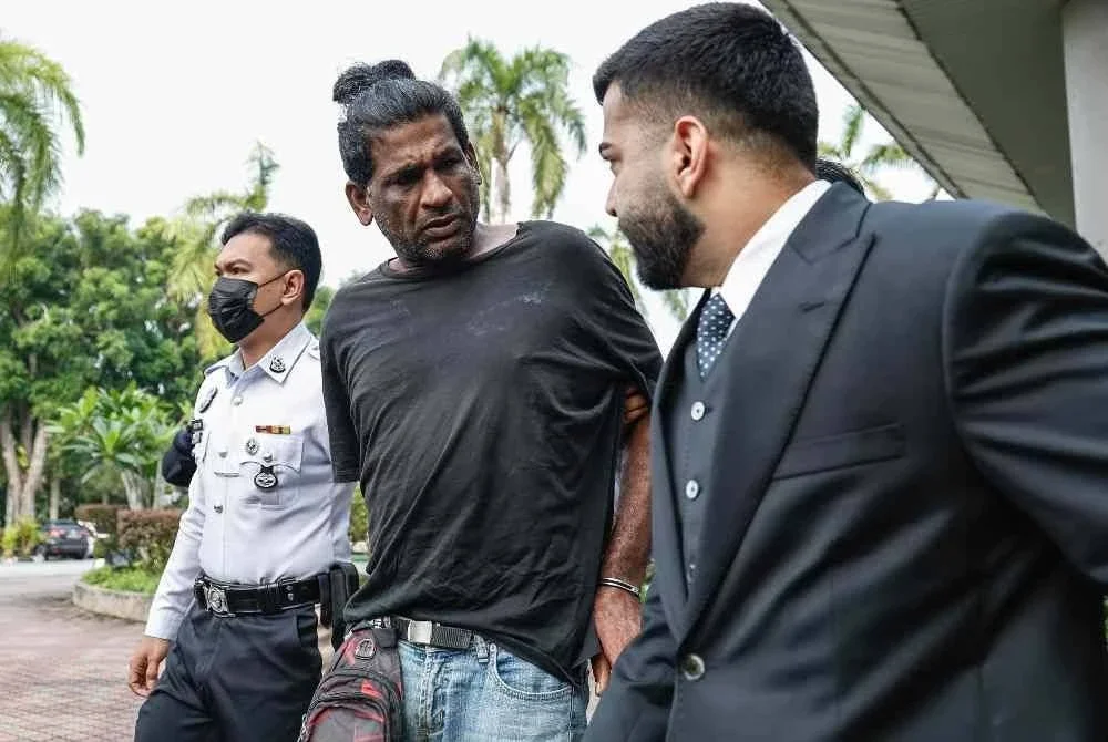 Agilan (tengah) dibawa keluar dari Mahkamah Majistret Shah Alam pada Selasa. - FOTO: Bernama