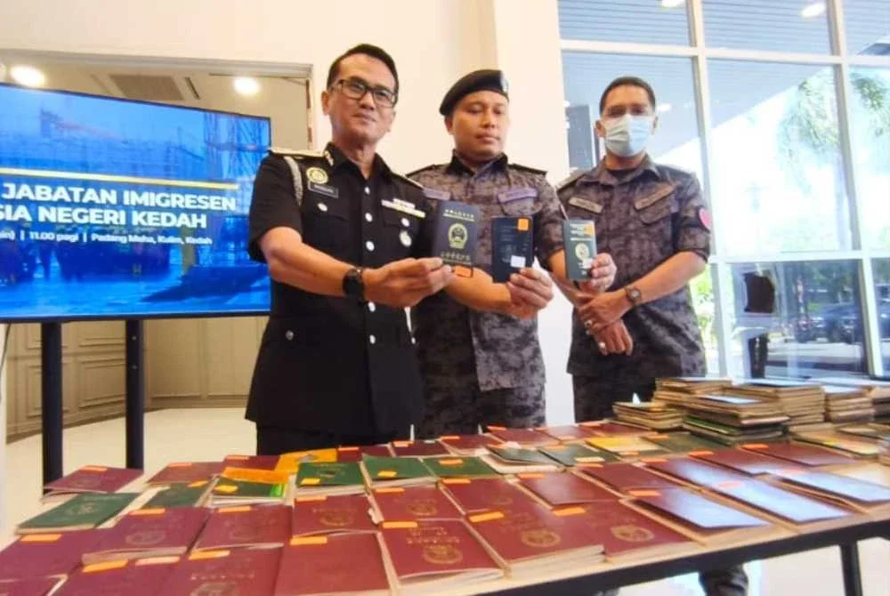Mohd Ridzzuan (kiri) menunjukkan pasport warga asing yang sedang disemak dan diteliti semasa sidang akhbar di Alor Setar pada Selasa.