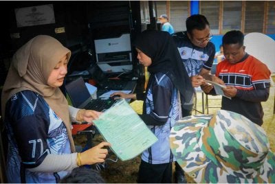 Kakitangan JPN membantu penduduk kampung yang hadir memperbaharui dokumen pengenalan diri pada Program Literasi Pendaftaran sempena sambutan Hari Pendaftaran Negara ke-78 Peringkat Kelantan di Pos Balar, Gua Musang pada Selasa. 