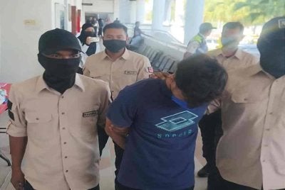 Tertuduh diiringi anggota polis untuk dituduh di Mahkamah Majistret pada Selasa. 