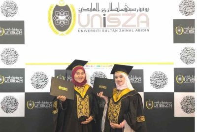 Dua graduan UniSZA, DaniaAinur (kiri) dan Nurhanieza teruja menggenggam Ijazah sempena Majlis Idul Ilmi Konvokesyen UniSZA ke-18 pada Selasa.