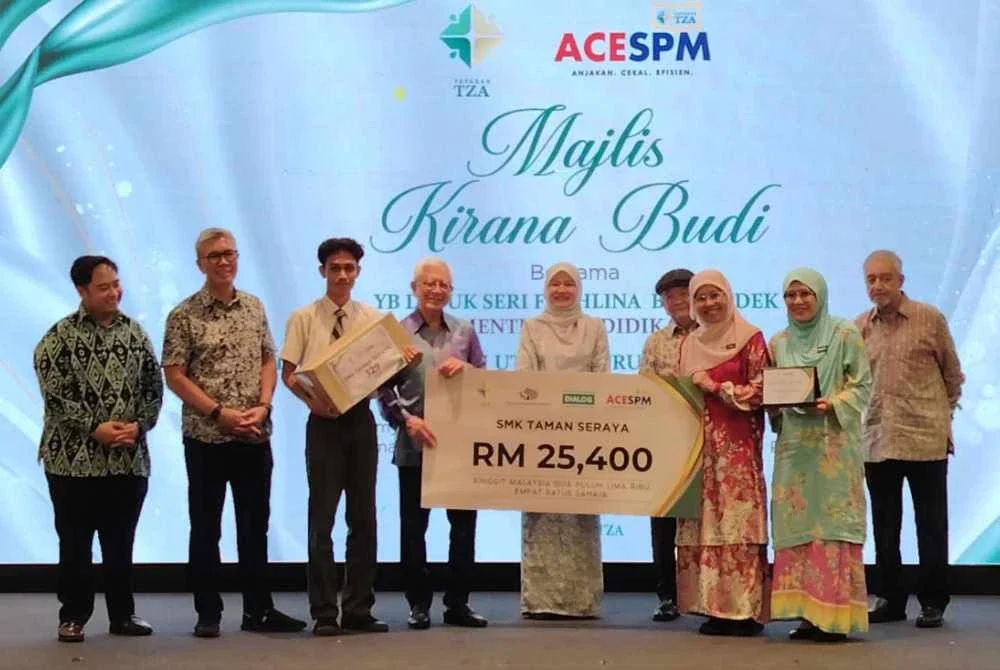 Arshad (tengah) diiringi Fadhlina (lima dari kanan) dan Zafrul (dua dari kiri) menyampaikan replika cek kepada wakil penerima dari SMK Taman Seraya