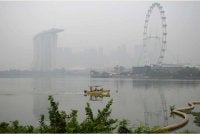 Sebuah bot melalui perairan berhampiran Marina Bay Sands ketika latar langit bandar Singapura diselubungi jerebu pada 15 Oktober 2026 susulan kebakaran hutan di Indonesia yang menjejaskan beberapa kawasan di rantau ini. - Foto AFP