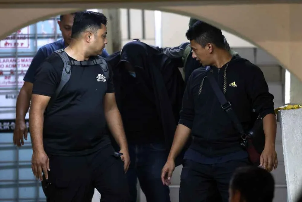 Suspek dibawa oleh anggota polis berhampiran kediaman di Kuarters Lapangan Terbang Antarabangsa Kuala Lumpur (KLIA) bagi membantu siasatan. Foto Bernama