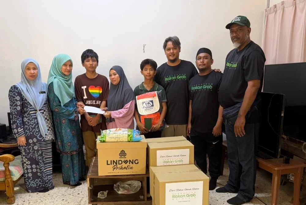 Ahli jawatankuasa PRGM yang diketuai Shanlee (tiga dari kanan) menyampaikan bantuan keperluan asas dan sumbangan tunai kepada keluarga Azira (empat dari kiri). Turut hadir, Pegawai Prihatin Sinergi PERKESO Melaka, Izrawati Ibrahim (kiri).