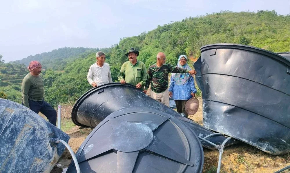 Abdul Rahim (tengah) bersama sebahagian Pekebun Rancangan Pertanian Berkelompok Ulu Chemor melihat kerosakan tangki air di kebun mereka akibat gangguan gajah liar.