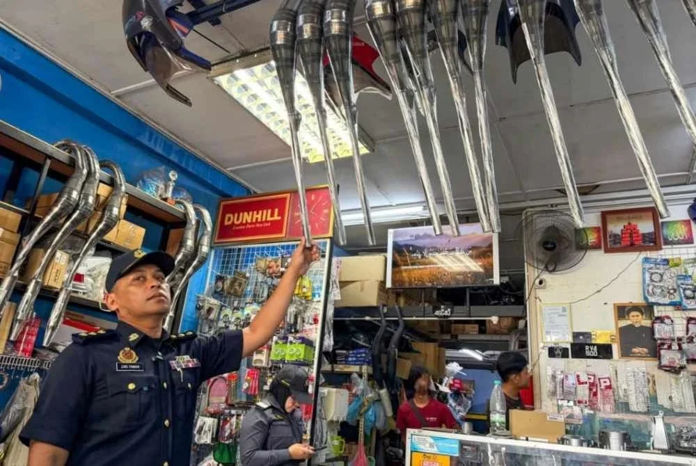 Seorang anggota JPJ meneliti aksesori yang dipamerkan di sebuah bengkel motosikal semasa Ops Bengkel dijalankan bersama KPDN Pahang. Foto JPJ Pahang