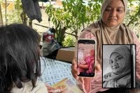 Marliza memegang gambar Norhazwani (gambar kecil) di telefon bimbit dan ditatap anak sulung mangsa.