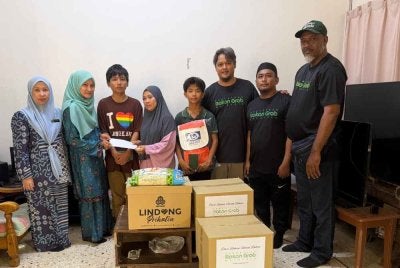 Ahli jawatankuasa PRGM yang diketuai Shanlee (tiga dari kanan) menyampaikan bantuan keperluan asas dan sumbangan tunai kepada keluarga Azira (empat dari kiri). Turut hadir, Pegawai Prihatin Sinergi PERKESO Melaka, Izrawati Ibrahim (kiri).