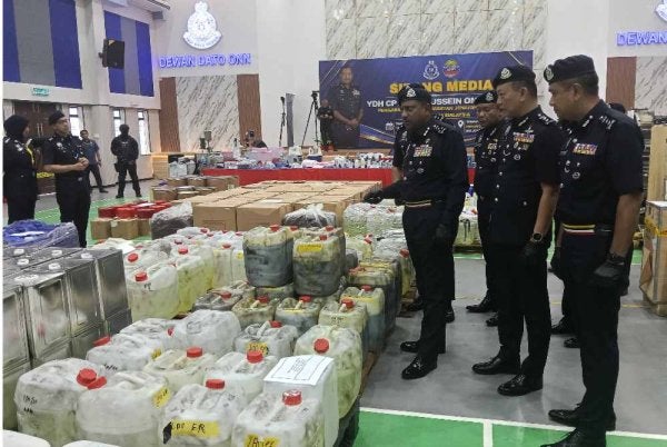 Hussein (kiri) menunjukkan peralatan dan bahan prekursor yang dipercayai digunakan dalam kegiatan pemprosesan dadah