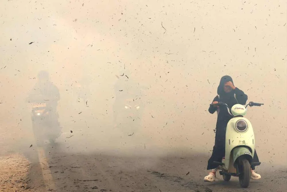 Penunggang motosikal meredah asap tebal kebakaran di Lampung Sungai Tabuk, Kabupaten Banjar, Kalimantan Selatan. Foto: MUDA SAGALA / AFP