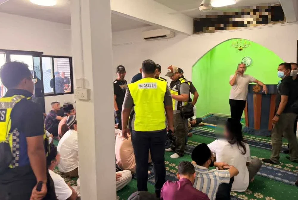 Pegawai Imigresen menjalankan pemeriksaan terhadap individu ditahan dalam serbuan dijalankan pada Jumaat.