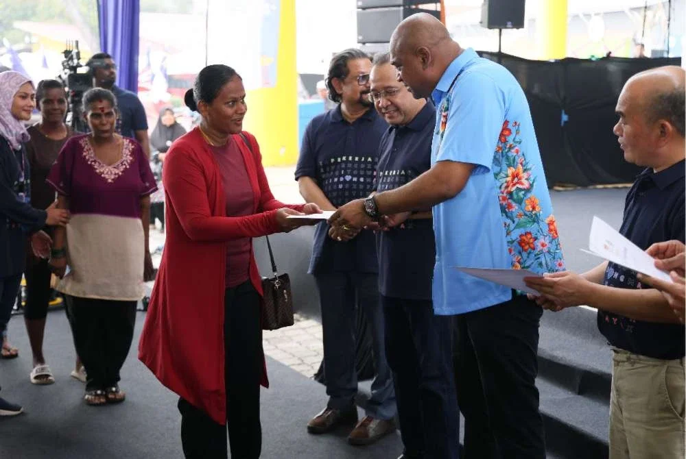 Ramanan (dua dari kanan) menyampaikan sijil skim LINDUNG Kasih kepada suri rumah pada program i LINDUNG u Gegar di Dataran Keris, Melaka pada Sabtu. Foto: Bernama