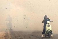 Penunggang motosikal meredah asap tebal kebakaran di Lampung Sungai Tabuk, Kabupaten Banjar, Kalimantan Selatan. Foto: MUDA SAGALA / AFP