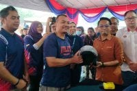 Mohd Azlan (dua dari kanan) menyerahkan topi keledar percuma kepada pengunjung sempena PMK Kepayang 2026 di Dewan Greentown pada Sabtu.