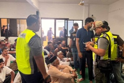 Pegawai Imigresen menjalankan pemeriksaan terhadap individu ditahan dalam serbuan dijalankan pada Jumaat.