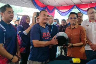 Mohd Azlan (dua dari kanan) menyerahkan topi keledar percuma kepada pengunjung sempena PMK Kepayang 2026 di Dewan Greentown pada Sabtu.