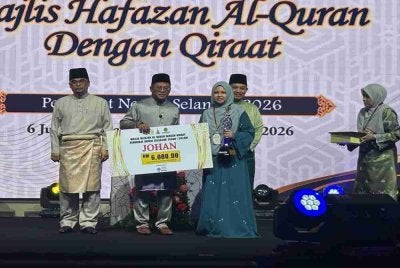Amirudin (tengah) menyampaikan hadiah kemenangan kepada johan kategori wanita Hafazan Al-Quran dengan Qiraat Peringkat Negeri Selangor di Dewan Syarahan dan Muzakarah Islam di sini pada Sabtu.