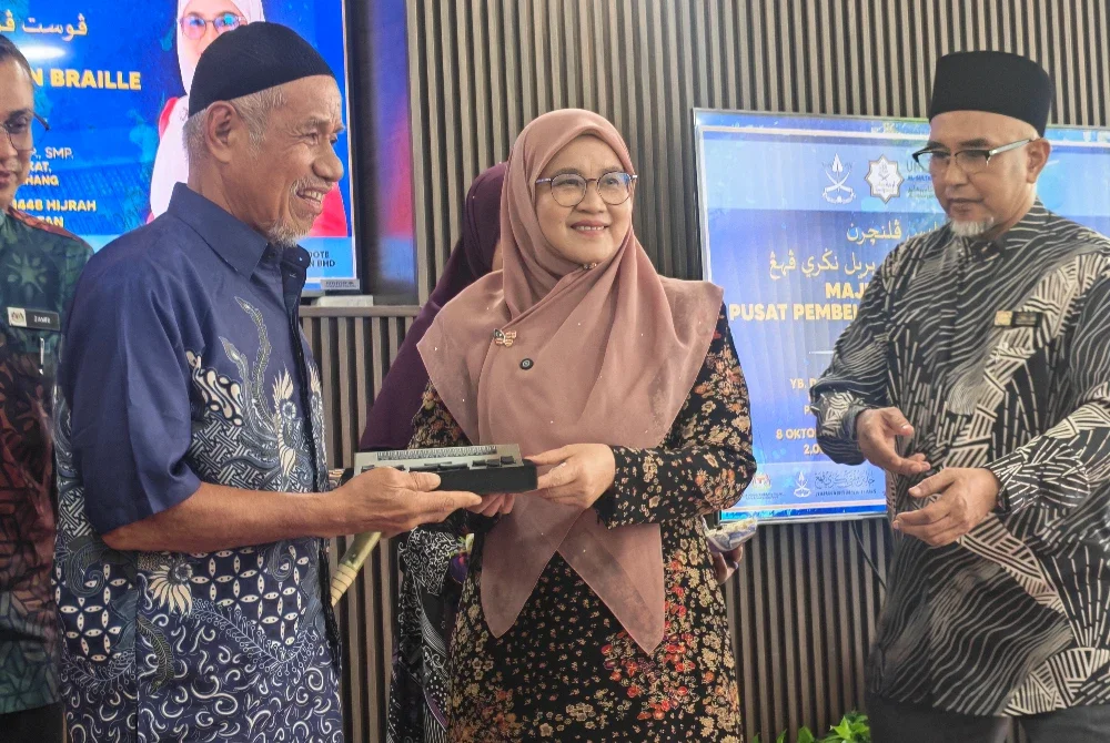 Sabariah (tengah) menyampaikan peranti e- Braille kepada salah seorang wakil selepas Majlis Pelancaran Pusat Pembelajaran Al-Quran Braille Negeri Pahang di Masjid Tepian Putra baru-baru ini.