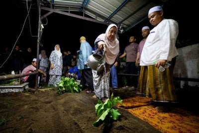 Ahli keluarga menyiram air di pusara pegawai Agensi Kawalan dan Perlindungan Sempadan Malaysia (AKPS), Norhazwani Ibrahim, 35, selepas jenazahnya dikebumikan di Tanah Perkuburan Islam Tanjong, Pengkalan Kubor, awal pagi tadi. - Foto Bernama