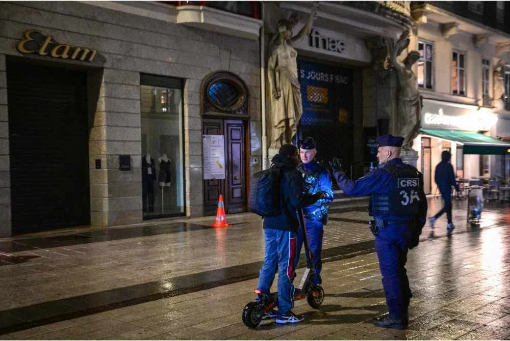 Pegawai polis Perancis memeriksa seorang individu semasa perintah berkurung dilaksanakan di Lyon pada 19 Oktober 2026 - Foto: AFP