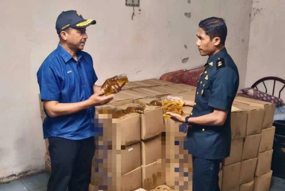 Muhammad Nizam (kiri) memeriksa minyak masak peket bersubsidi yang ditemui di gudang pakaian tersebut.