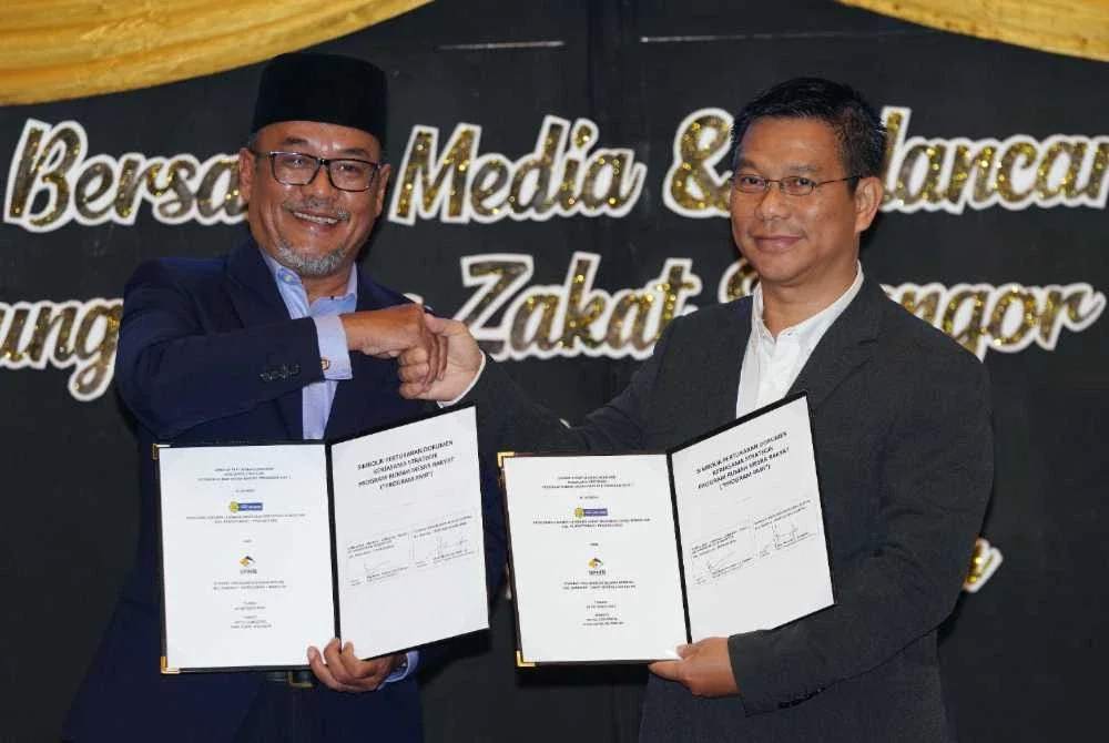 Mohd Khaidzir (kiri) dan Ketua Pegawai Eksekutif SPNB, Abdul Hamid Abdullah (kanan) melakukan simbolik pertukaran dokumen kerjasama strategik Program SPNB pada Sepetang bersama Media dan Pelancaran Kempen Hujung Tahun Zakat Selangor di sini, Selasa.