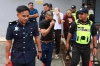 Tertuduh (tengah) ketika dihadapkan di Mahkamah Majistret Marang pada Selasa atas dakwaan membunuh rakan banduan pada Ogos lalu.