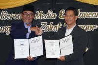 Mohd Khaidzir (kiri) dan Ketua Pegawai Eksekutif SPNB, Abdul Hamid Abdullah (kanan) melakukan simbolik pertukaran dokumen kerjasama strategik Program SPNB pada Sepetang bersama Media dan Pelancaran Kempen Hujung Tahun Zakat Selangor di sini, Selasa.