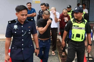Tertuduh (tengah) ketika dihadapkan di Mahkamah Majistret Marang pada Selasa atas dakwaan membunuh rakan banduan pada Ogos lalu.
