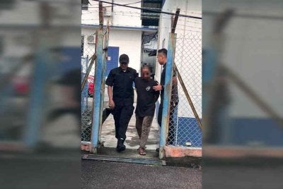 Suspek (tengah) dibawa keluar dari lokap menuju ke bilik mahkamah bagi mendapatkan perintah reman. 